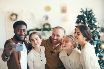 Group of elegant adult people smiling at camera while taking selfie photo during Christmas party, copy space