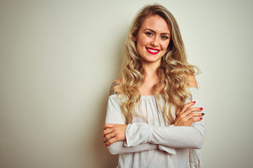 Young beautiful woman standing over white isolated background happy face smiling with crossed arms looking at the camera. Positive person.