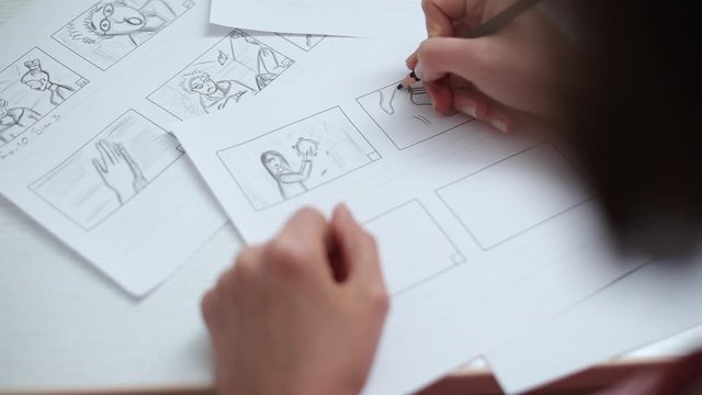 Hands draw with a pencil the storyboard for the film. 