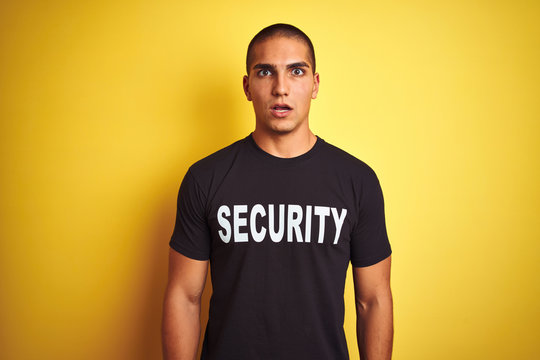 Young safeguard man with security t-shirt over yellow isolated background scared in shock with a surprise face, afraid and excited with fear expression
