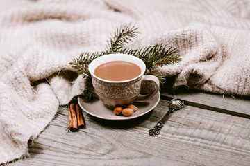 Obraz na płótnie Canvas Hot coffee cup with cozy blanket on a wooden table with decorations