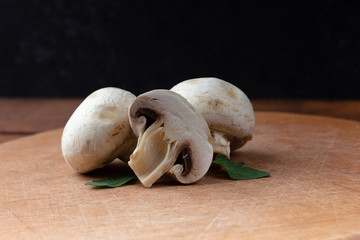 Raw Mushrooms on a wooden board on a brown background. Healthy food, veggie. Copy space