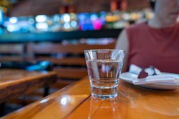 Glass of water in front of woman in dining restaurant table