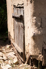 Old weathered wooden door of cob goat house with rusty metal hook