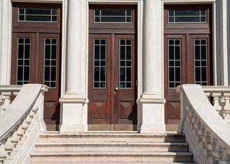 Outdoor staircase leading to large wooden double doors in classic setting