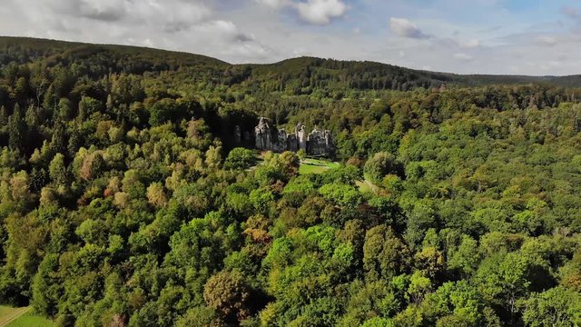 An aerial view of the famous sandstone rocks Externsteine in Germany. The autumn forest is already very colorful in September and sunlight shines on the rocks.