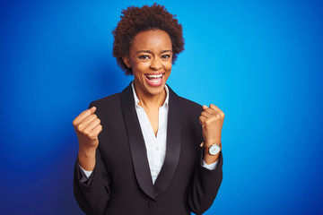African american business executive woman over isolated blue background very happy and excited doing winner gesture with arms raised, smiling and screaming for success. Celebration concept.