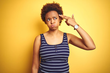 Beauitul african american woman wearing summer t-shirt over isolated yellow background Shooting and killing oneself pointing hand and fingers to head like gun, suicide gesture.