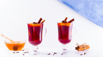Glass of hot mulled wine with spices and honey on white background. Christmas mulled wine with orange, star anise and cinnamon. Two glasses of winter Christmas drink