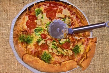 baked round pizza with sliced chicken and broccoli