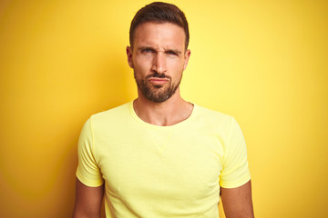 Young handsome man wearing casual yellow t-shirt over yellow isolated background skeptic and nervous, frowning upset because of problem. Negative person.