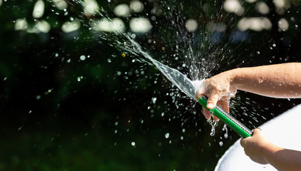 Kid playing with water sprinkler in the garden