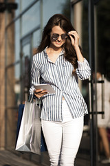 Fototapeta premium Woman walks with packages after shopping and uses a tablet.