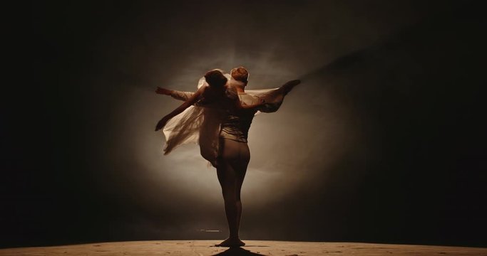 Professional duet of ballet dancers performing on stage isolated on smoked black background. Young choreographers showing their creative art 4k footage