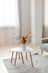 bouquet of cotton in a vase on the table. decorative elements of the interior. white coffee table by the sofa