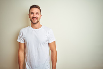 Young handsome man wearing casual white t-shirt over isolated background with a happy and cool smile on face. Lucky person.