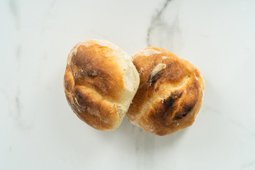Two fresh rolls taken straight from the oven on a marble background.