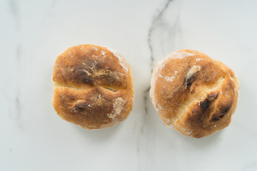 Two fresh rolls taken straight from the oven on a marble background.