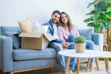 Young couple in love hugging sitting on the sofa very happy moving to a new home