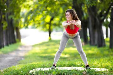 Young beautiful woman practicing yoga in the green park. Wellness concept. Calmness and relax, woman happiness.