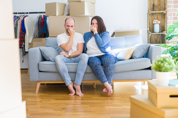 Young couple sitting on the sofa arround cardboard boxes moving to a new house smelling something...