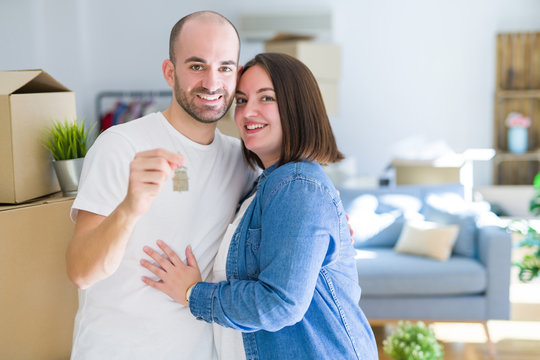 Young couple smiling very happy showing keys of new home, moving and buying new apartmet concept