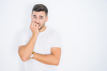 Young handsome man wearing casual white t-shirt over white isolated background looking stressed and nervous with hands on mouth biting nails. Anxiety problem.