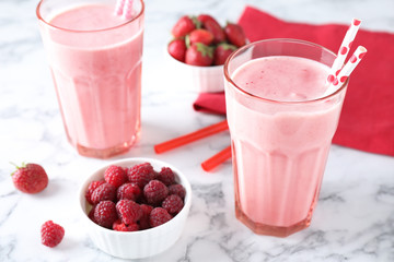 Tasty milk shakes and berries on white marble table