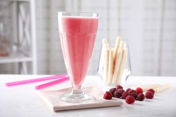 Tasty milk shake and raspberries on white wooden table