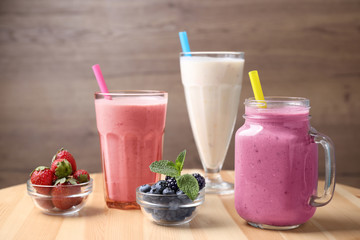 Different milk shakes and berries on wooden table