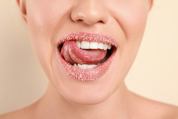 Young woman with sugar lips on beige background, closeup