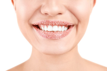 Fototapeta premium Young woman with sugar scrub on lips against white background, closeup