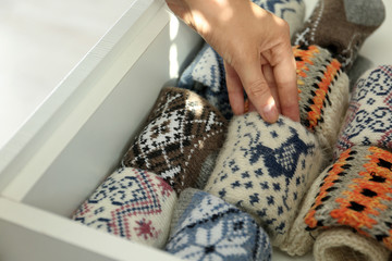 Woman taking warm knitted socks out of drawer indoors, closeup