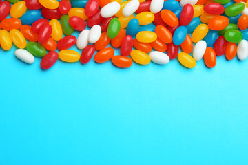 Tasty colorful jelly beans on blue background, flat lay. Space for text