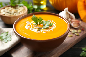 Delicious pumpkin soup in bowl on wooden table