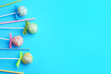 Tasty cake pops and straws on light blue background, flat lay. Space for text