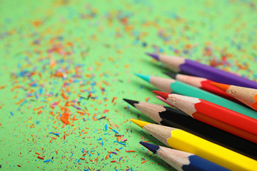 Color pencils and shavings on green background, closeup