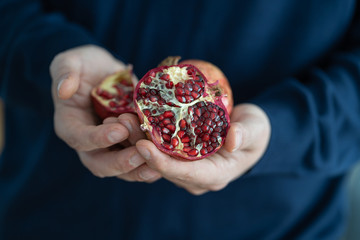 The man is holding a pomegranate in his hands. Exotic ingredient of fresh juice.