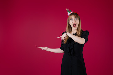 woman wearing funny christmas hoop pointing at copyspace on her hand isolated over red