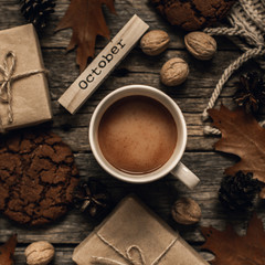 Cup of cocoa, cookies, nuts, dried autumn leaves on  wood background. Autumn composition.