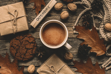 Cup of cocoa, cookies, nuts, dried autumn leaves on  wood background. Autumn composition.
