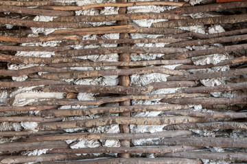 Old wall made of wooden sticks and cement