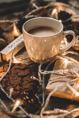 Cup of cocoa, garland, cookies, nuts, dried autumn leaves on  wood background. Autumn composition.