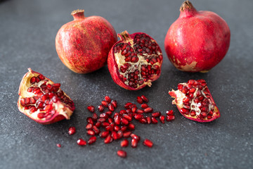 Different parts of the pomegranate fruit lie on the kitchen counter. Pomegranate on a black background.