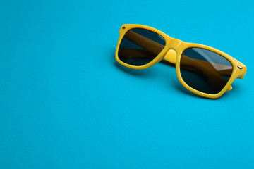 Stylish sunglasses on blue background, space for text. Fashionable accessory