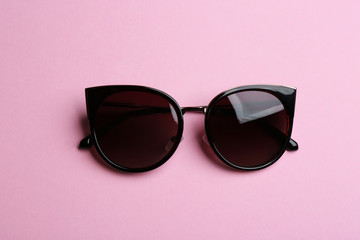 Stylish sunglasses on pink background, top view. Fashionable accessory