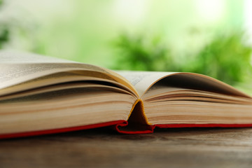 Open hardcover book on wooden table against blurred background closeup