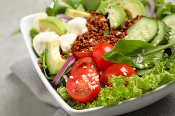 Delicious avocado salad with quinoa on light grey table, closeup