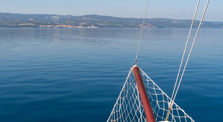 Bow of frigate ship against blue sea.