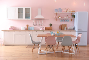 Stylish pink kitchen interior with dining table and chairs